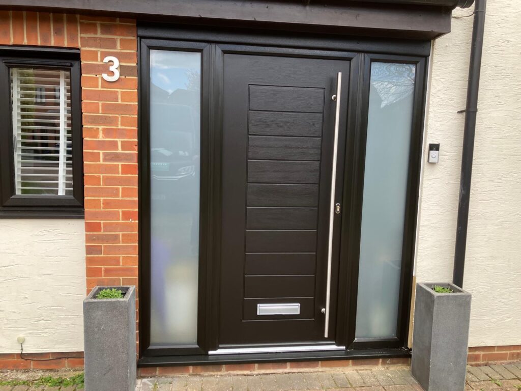 Dark woodgrain composite front door fitted in a brick house