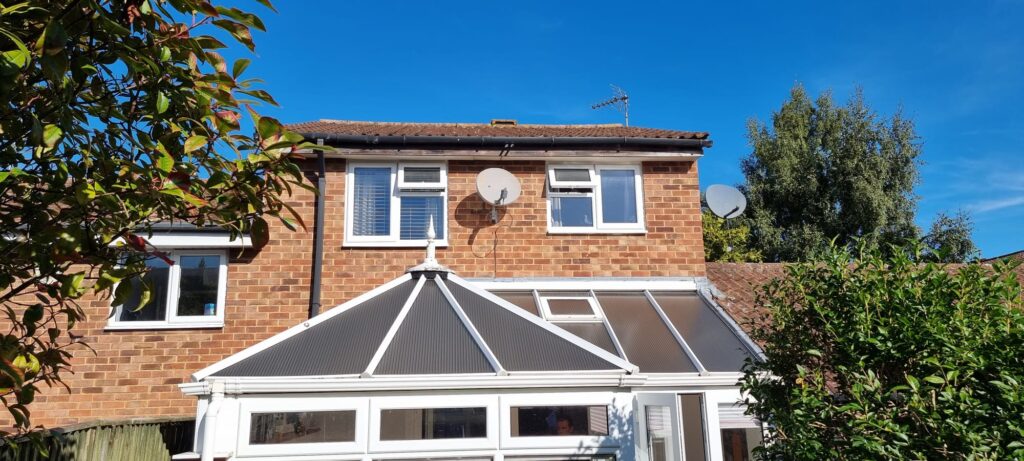 Grey tiled conservatory roof with windows on a brick house