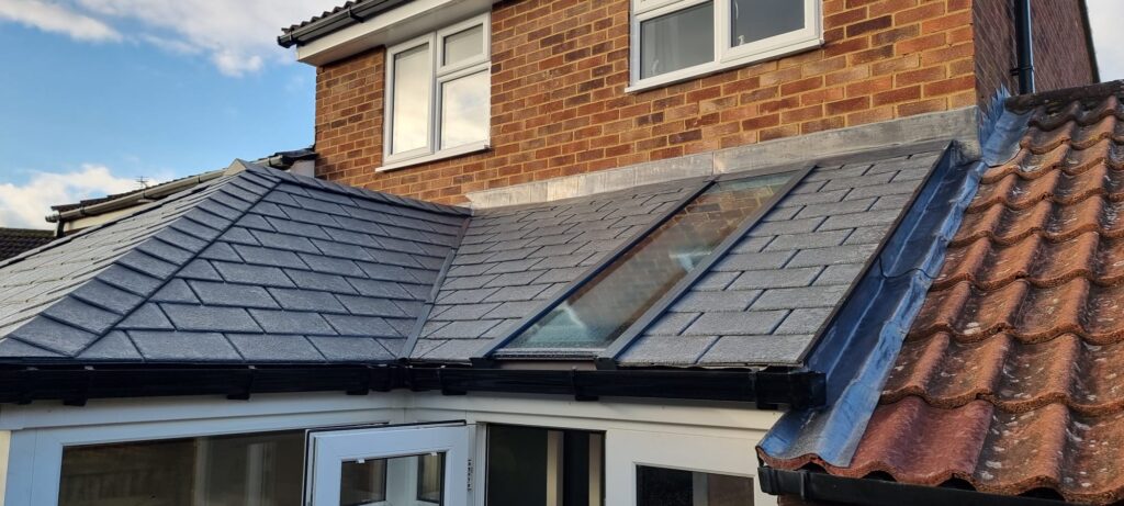 Grey lightweight tiled conservatory roof beside a traditional clay tiled roof